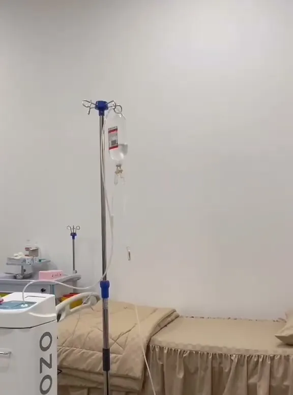 Tiang infus dan tempat tidur pasien di ruang tindakan